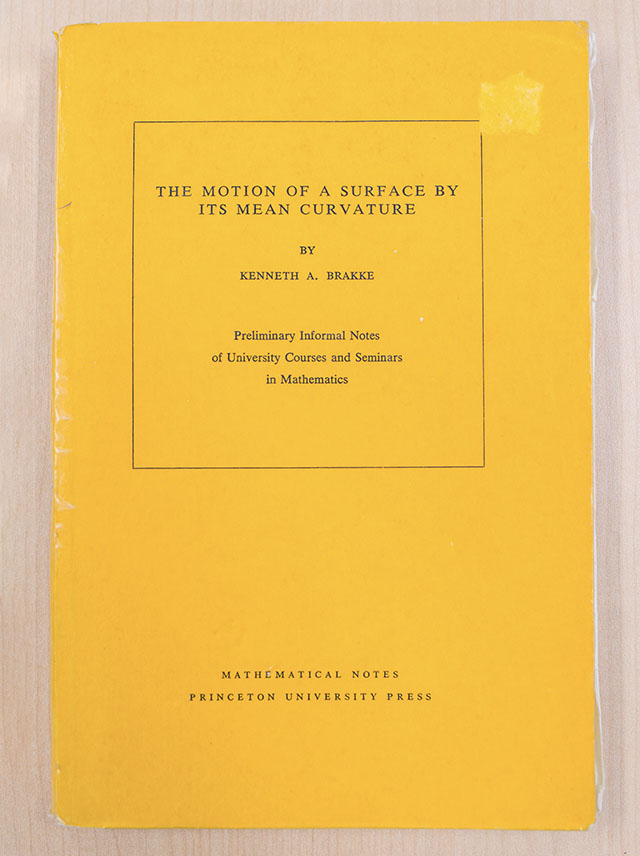 1978年にブラッケが出版した著書『The Motion of a Surface by Its Mean Curvature』。幾何学的測度論を用いた平均曲率流についての非常に革新的な内容であったが、数学の理論の確立には至っていなかった。